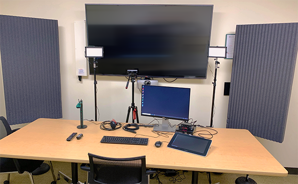 Mini recording studio showing setup of computer monitor and keyboard, large wall display, video camera, Wacom tablet, document camera, and connections for laptop