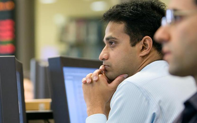 two people stare at computer screens lost in thought