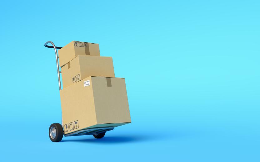 a handcart stacked with moving boxes rolls across a blue background