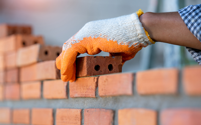 Person laying bricks to build a wall