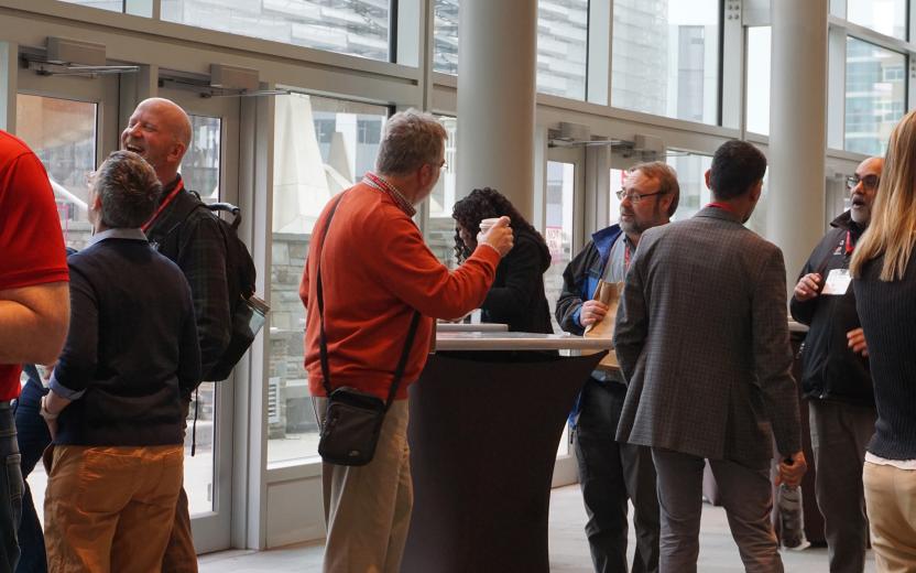 Small groups of co-workers stand around tall tables and converse over coffee