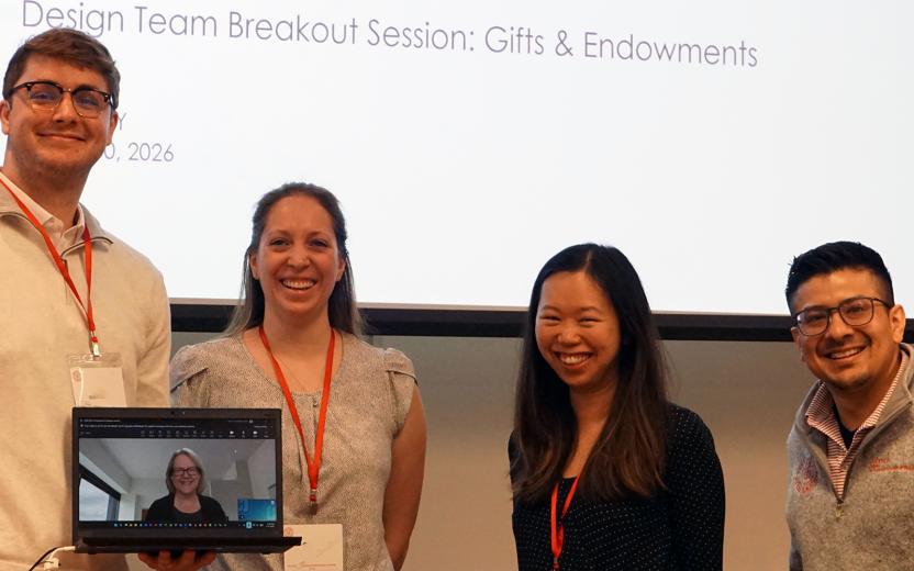 a photo of four employees meeting in person with another colleague joining by video conference