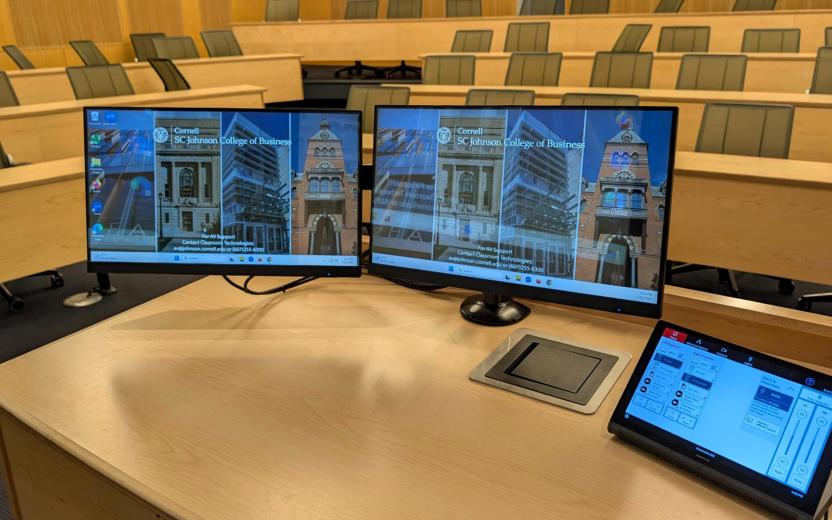 an instructor's desk with monitors and tablet displaying a new touch pad control interface for the clasroom technology
