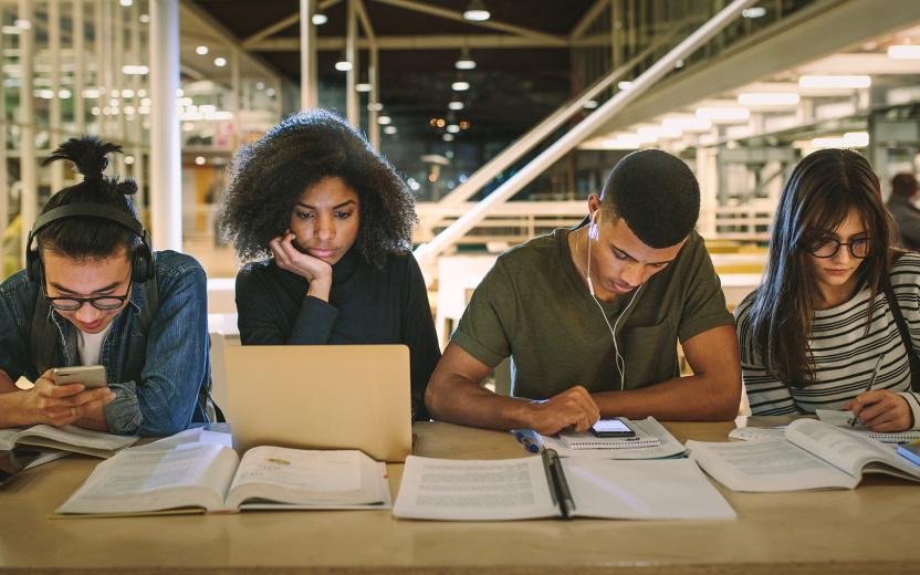students in a library using different technologies