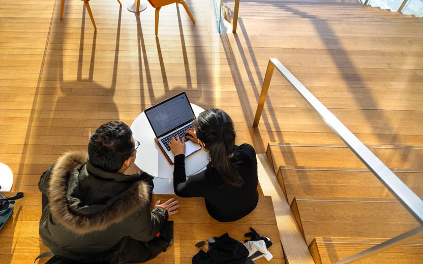 Students with laptop on stairs.