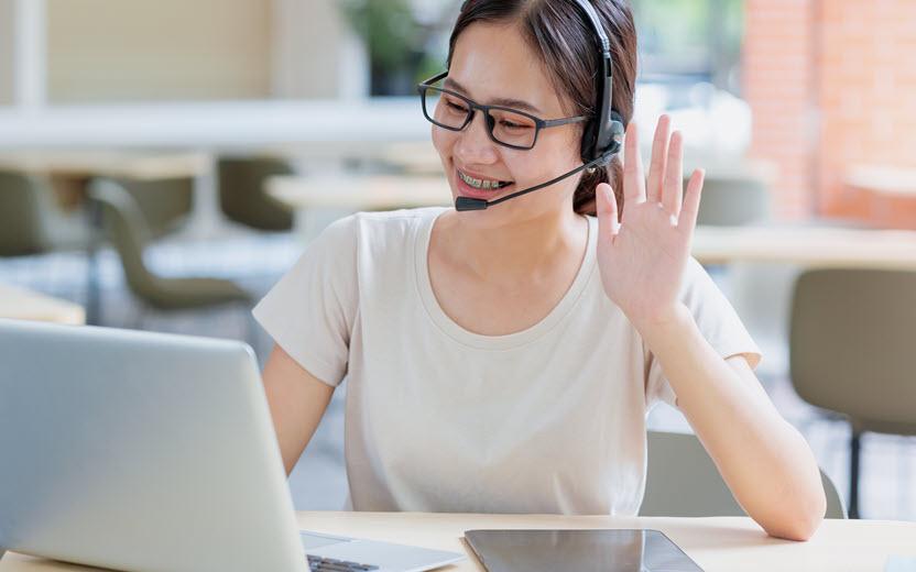 Young woman with raised hand during online video meeting