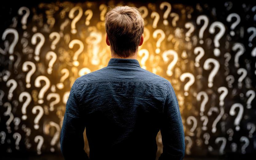 The back of a man staring at a field of question marks