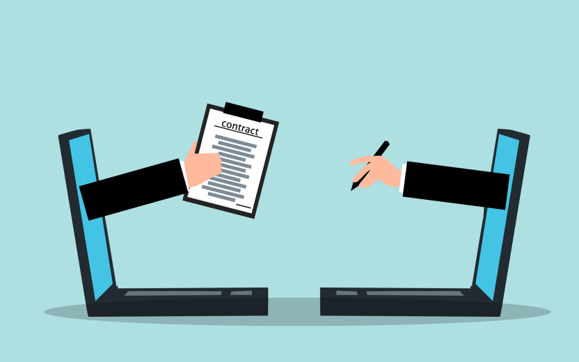 One hand reaches out of a laptop holding a contract, opposite another hand reaching out and holding a pen.