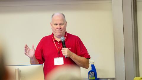 In a classroom presentation, the speaker addresses the audience through a handheld microphone.