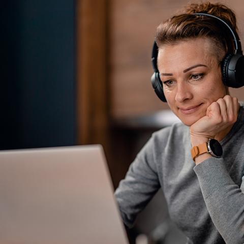 Person on a laptop listening with headphones