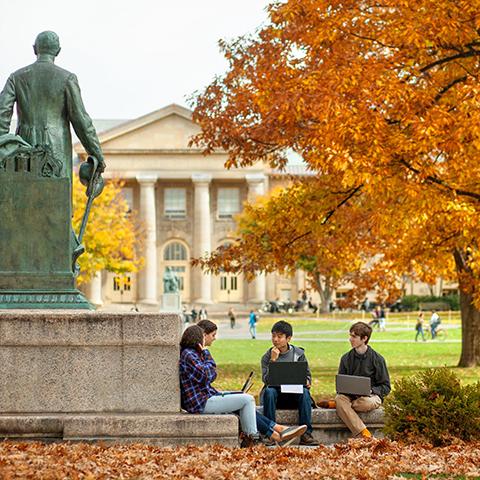 Students with computers near statue of Ezra Cornell
