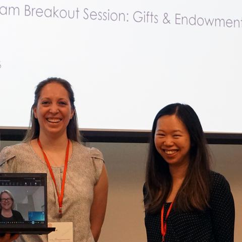 a photo of four employees meeting in person with another colleague joining by video conference