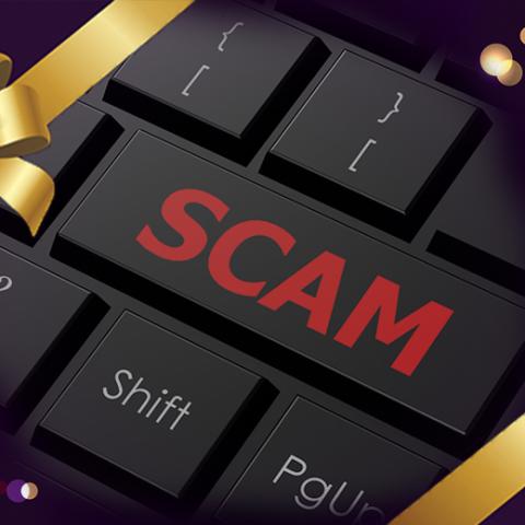 A black keyboard with the word SCAM on one of the keys in all red letters, with a gold holiday ribbon, bow, and bokeh lights bordering the image.