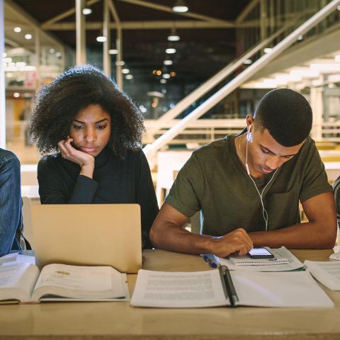 students in a library using different technologies