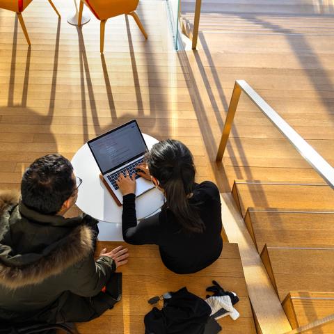 Students with laptop on stairs.