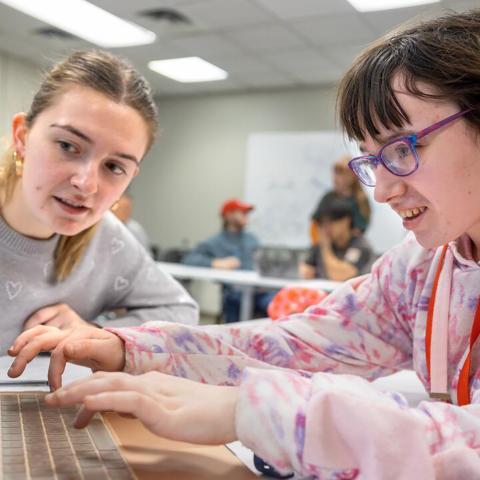 Two students explore web accessibility on a laptop at a table